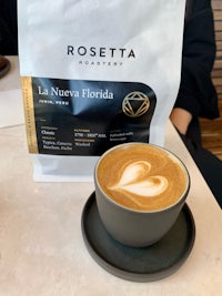 a cup of coffee sitting on top of a bag of coffee