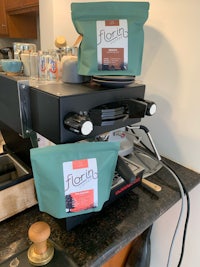 two bags of coffee sitting on top of an espresso machine