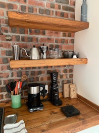 a kitchen with wooden shelves and a coffee maker